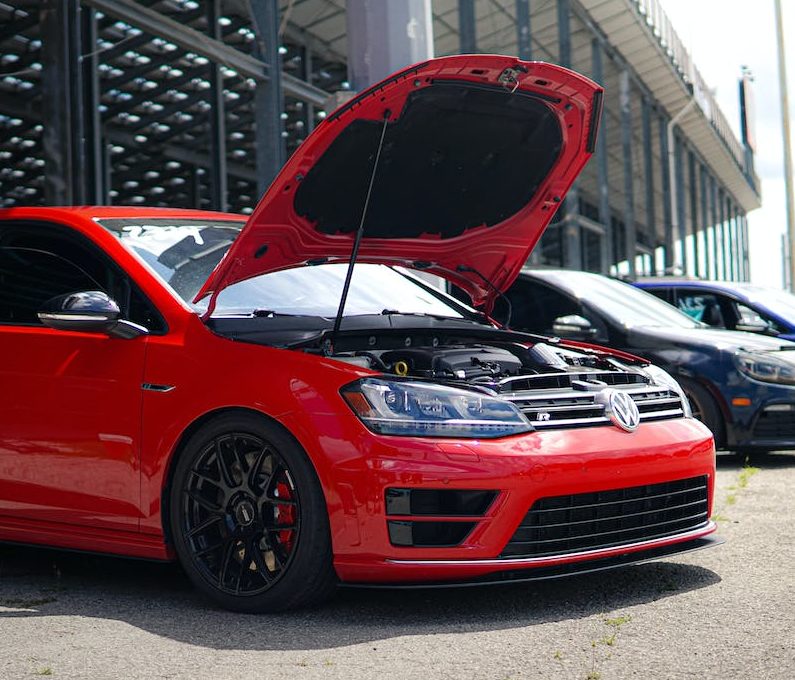 A red volkswagen golf gti with its hood open.