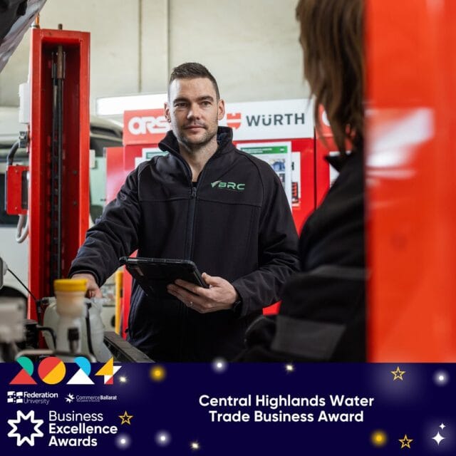 Two individuals in work attire stand in a workshop. One holds a tablet, engaging with the other. The image includes a banner for the 2024 Central Highlands Water Trade Business Award.